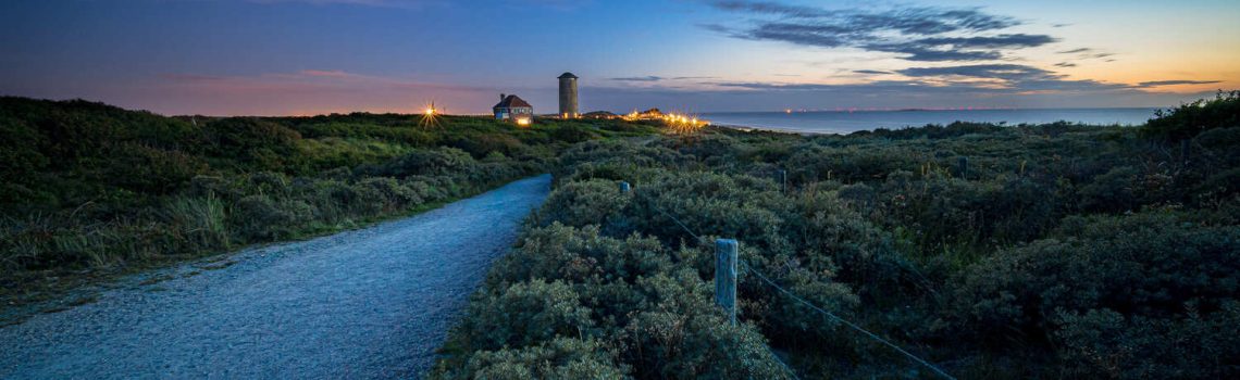 caminho-cercado-por-arbustos-e-vegetacao-que-leva-um-povoado-e-um-mar-ao-por-sol